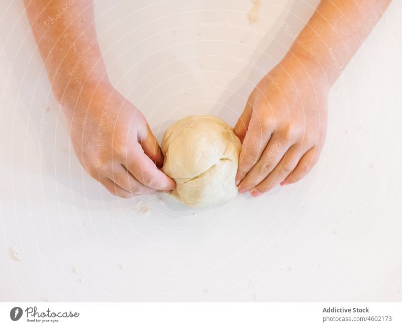 Anonymous boy kneading dough in kitchen cook kid flour pastry helper tear apron process bake food domestic child kitchenware culinary product messy dirty