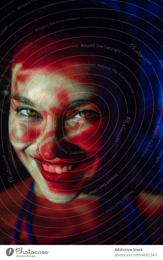 Smiling woman in dark with light projection illuminate projector portrait glow smile concept gaze cover face red female dusk young illusion night lady creative