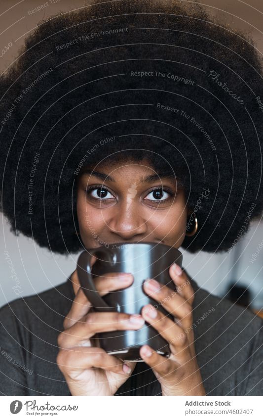 Positive black woman with hot beverage cup hot drink coffee afro feminine hairstyle dreamy smile appearance happy charming brunette attractive female cheerful