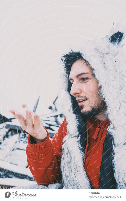 Young man enjoying a snowy day wearing a fur hat and a red hoodie winter fun funny cold freeze frozen life lifestyle white caucasian beard attractive cool fresh