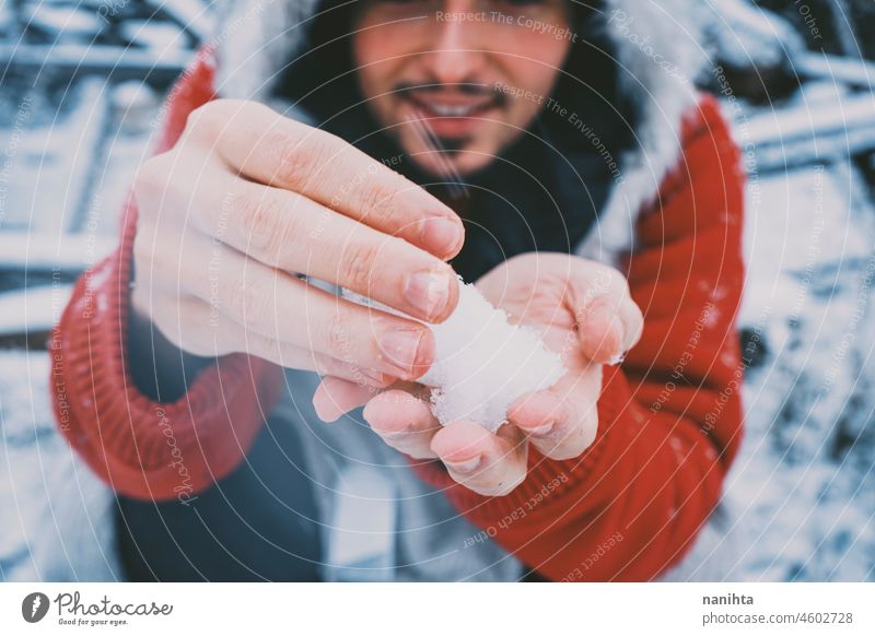 Young man enjoying a snowy day wearing a fur hat and a red hoodie winter fun funny cold freeze frozen life lifestyle white caucasian beard attractive cool fresh