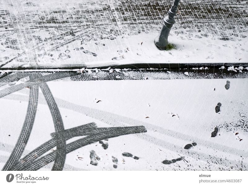 Bird's eye view of footprints and car tire tracks on the snow-covered road and paved footpath with street lamp / driving away / winter Winter Car tracks