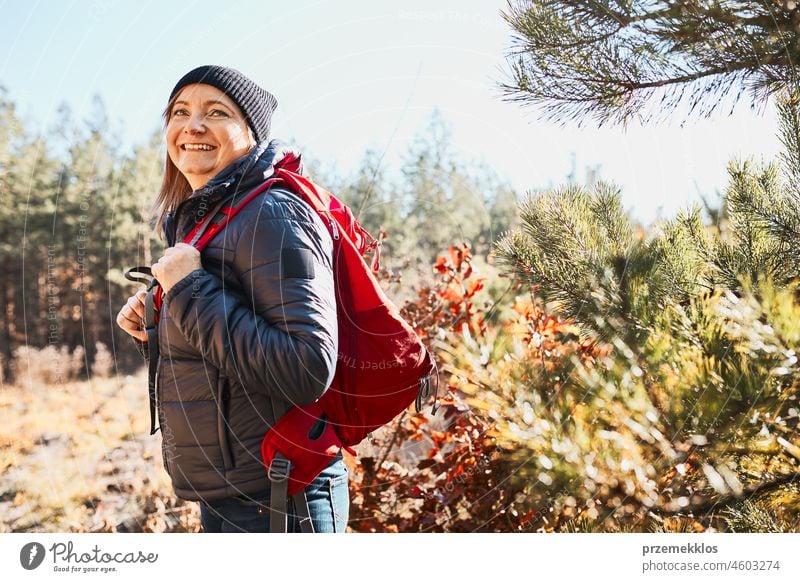 Smiling woman enjoying hike on sunny vacation day. Female with backpack walking through forest trip hiking adventure travel summer journey wanderlust hiker