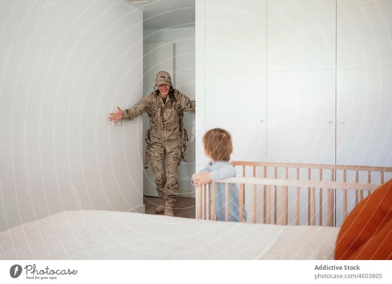Military woman walking to son in crib mother military soldier bedroom back home army smile duty boy motherhood patriot child cute happy love together childcare