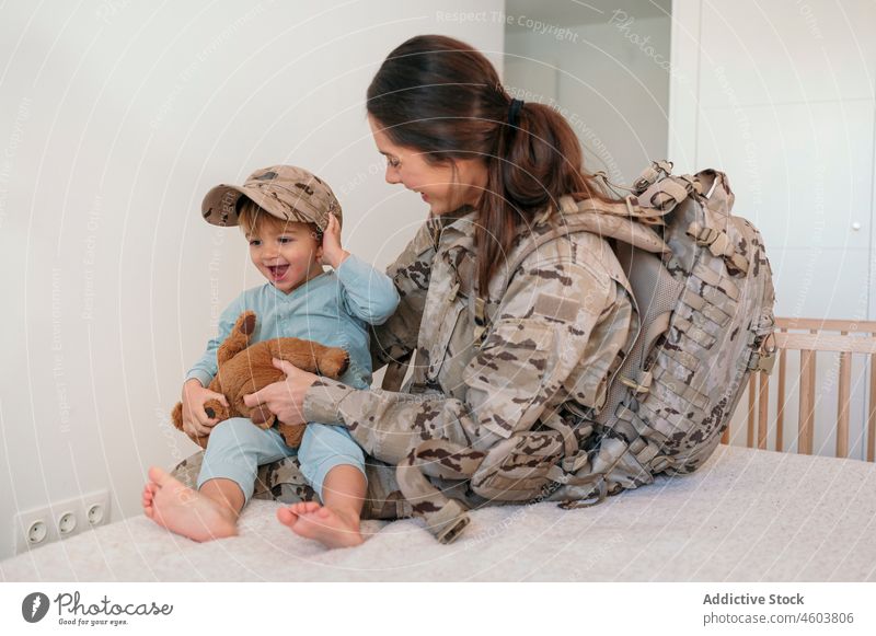 Military woman putting cap on son mother military happy soldier army duty boy smile motherhood play toy patriot child cute love together delight childcare