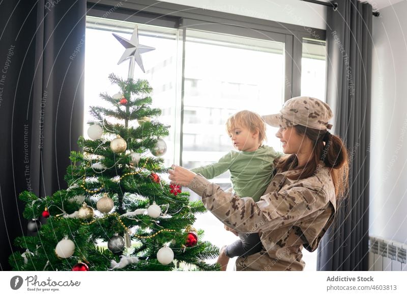 Military mom with son decorating Christmas tree mother military soldier duty boy motherhood christmas tree decorate xmas delight holiday smile event december
