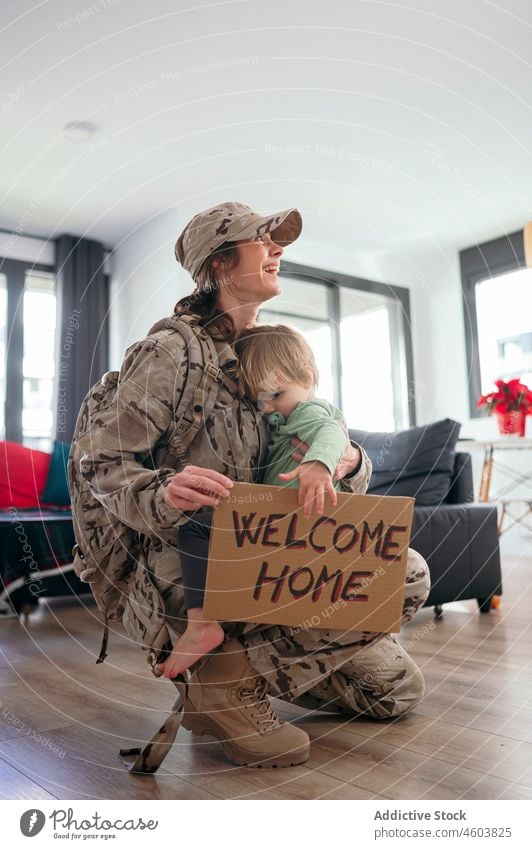 Content military woman hugging son with greeting board mother soldier duty boy service arrive welcome home inscription smile patriot child cute happy love