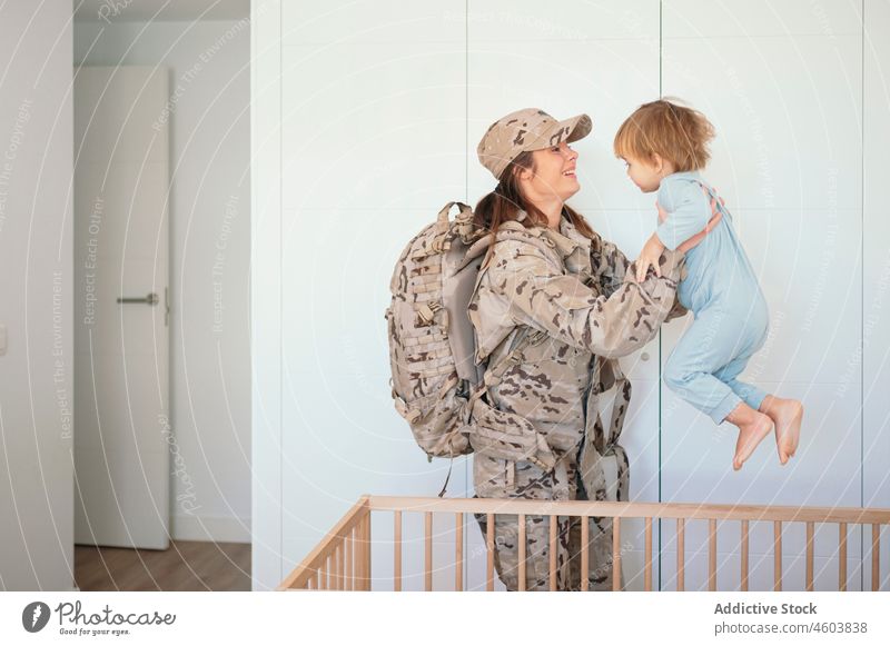 Caring military woman holding son mother soldier crib bedroom army duty patriot boy child cute love together childcare childhood home uniform camouflage