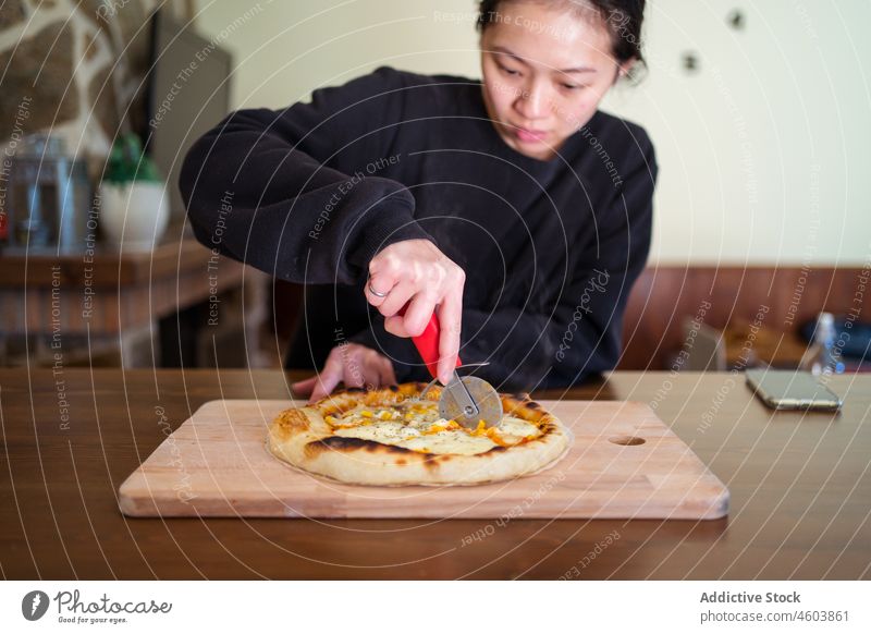 Asian woman cutting baked pizza cook kitchen culinary homemade italian cuisine cutter chef table female light lady housewife fresh gastronomy at home baker