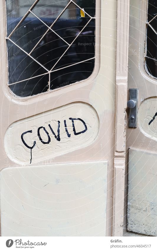 Covid is written on an old wooden front door - is this meant as a warning than a hint? Graffiti Scribbles Old run-down Apartment Building Characters Typography