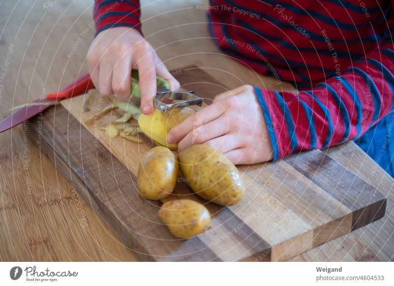 Child peels potatoes in the kitchen boil Kitchen Potatoes organic Slow food salubriously Vegetable Food upbringing children Knives Delicious