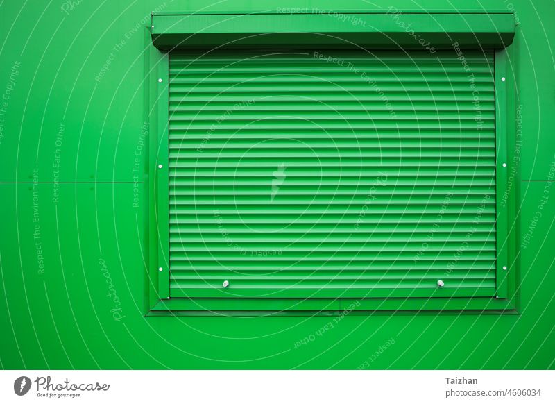 Green window shutter on green wall . security closed exterior light modern roller detail building apartment blind commercial condo contemporary cover entrance