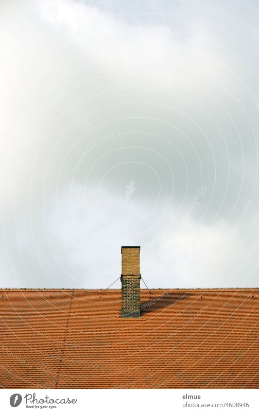 Chimney made of unrendered bricks of different color on a red tiled roof in front of slightly cloudy sky / heating costs Tiled roof Smoke extraction Clouds