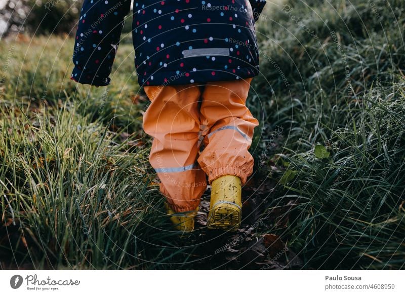 Rear view child with Yellow rubber boots Rubber boots Child childhood Winter Rain Grass Weather enjoyment outdoors Infancy water Exterior shot Wet Boots Joy