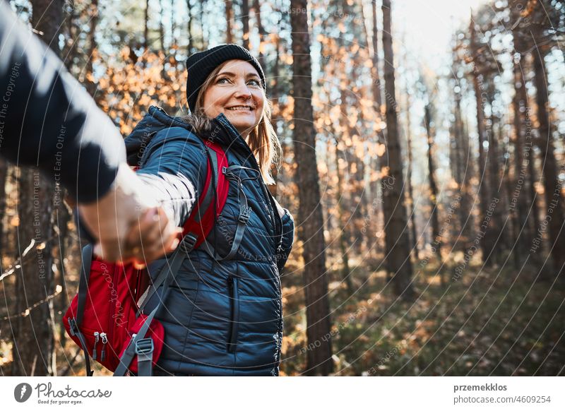 Couple holding hands enjoying trip while vacation day. Hikers with backpacks walking on forest path on sunny day hiking adventure travel gesture exploring
