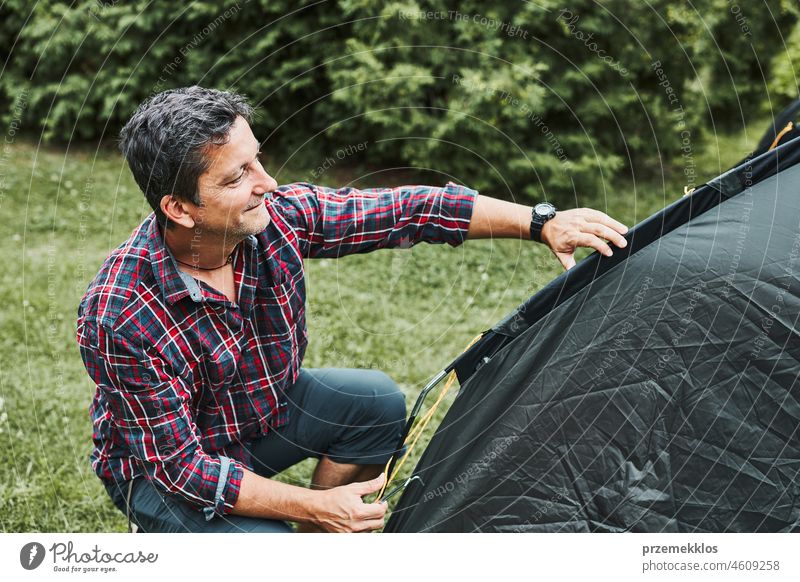 Man putting up a tent at camping during summer vacation. Preparing campsite to rest and relax. Spending vacations outdoors close to nature trip adventure