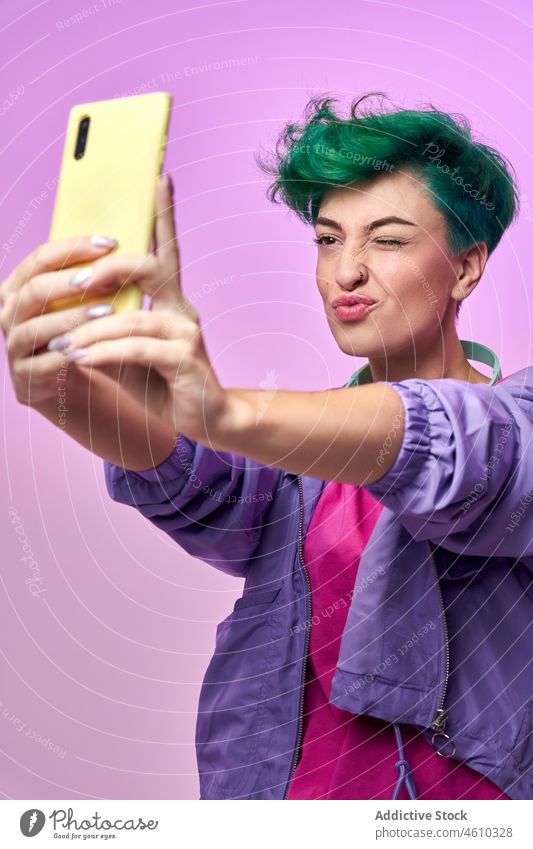 Cheerful millennial woman taking selfie smartphone self portrait social media headphones meloman style 80s fashion design retro studio green hair female model