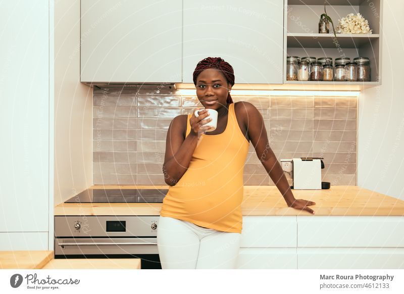 black pregnant woman taking a cup of coffee at the kitchen adult african apartment aroma beautiful beverage break breakfast brightness cafe caffeine