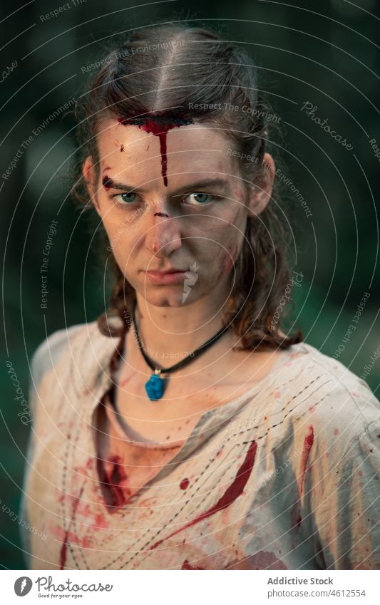 Injured woman in blood wearing viking costume at battle reconstruction brave confident historic medieval wound defense fight female gaze portrait reenactment