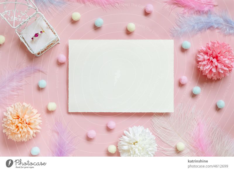 Blank card between pastel flowers, pom-poms and feathers near ring in a gift box on pink WEDDING envelope pompom mockup Flowers top view girlish paper valentine