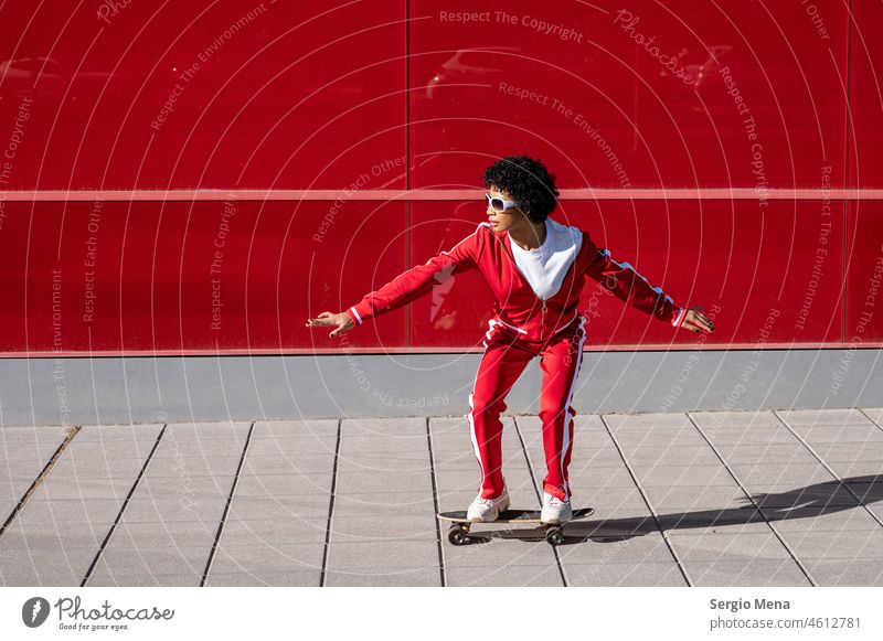 African American woman with short hair and red sportswear riding on her skateboard with red background african american female Spain Granada Red Sportswear