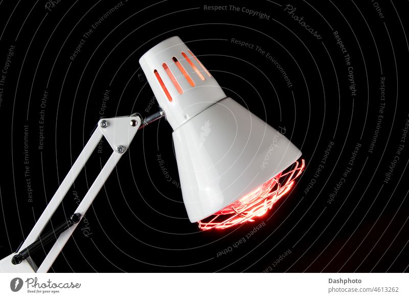 Illuminated Infra Red Health Lamp Closeup on a Black Background infra red lamp radiation white background electric glow glowing radiating base lamp shade pain