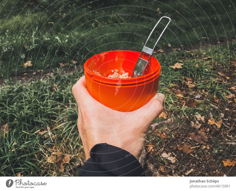 Muesli cup with folding spoon on a forest hike Cereal cup Mug Tin safekeeping Eating Meal Forest out outdoor Supplies Hiking Red Hand stop First person view