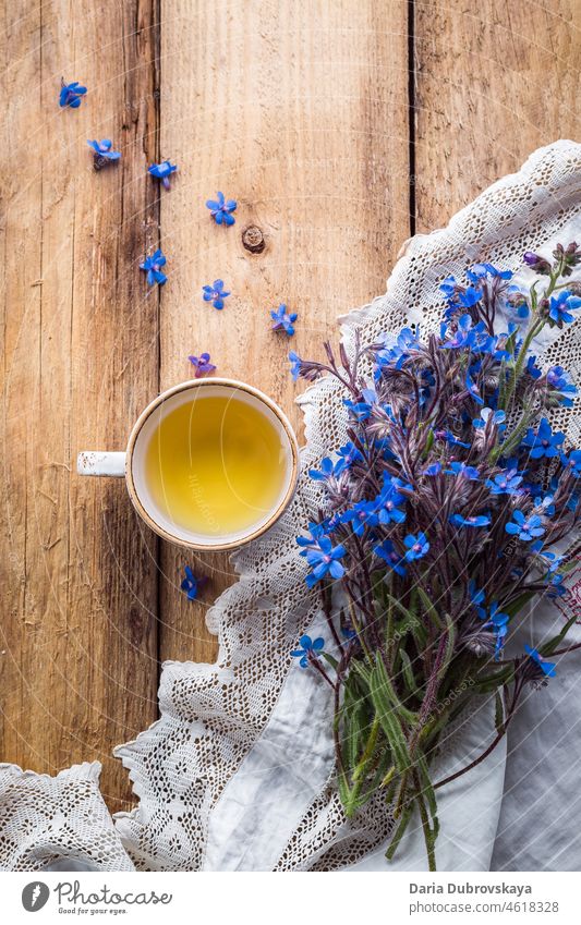 Bouquet of blue wildflowers and a cup of tea on a wooden table closeup breakfast frame knapweed design herb cornflower flora spring natural nature beauty bloom