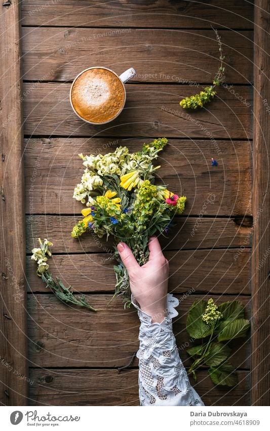 A bouquet of wildflowers in a female hand and a cup of coffee coffee break concept lifestyle woman foraging forage summer gatherings beautiful rustic moody