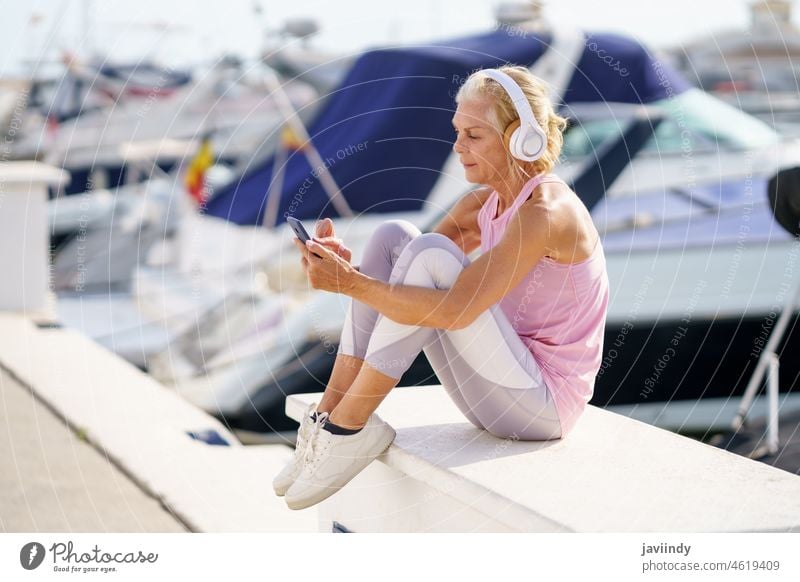 Mature sporty female taking a break to check a fitness app on her smartphone mature resting woman senior calories active workout runner person lifestyle