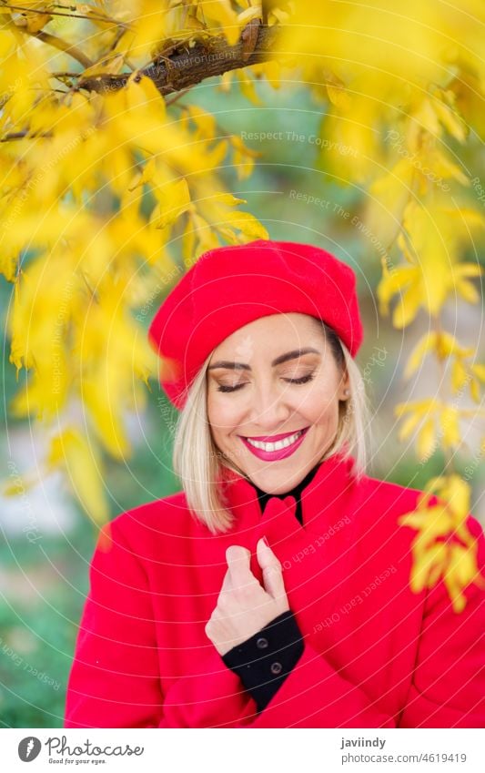 Happy middle-aged woman, smiling with her eyes closed among autumn leaves. winter red beret coat urban fall fashion female white season outdoor happy beauty