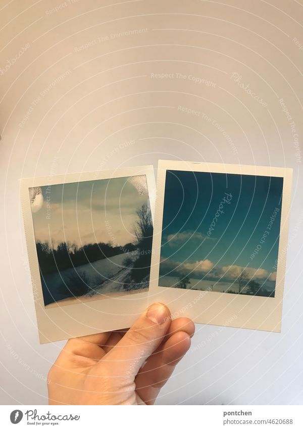 one hand holds two polaroids in front of a white wall. proudly looking at photos. look at Photos instant picture Photography Wall (building) Landscape Inn River