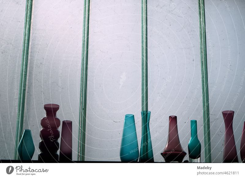 Colorful designer vases made of glass in the style of the sixties and seventies in front of a pane of frosted glass in an old workshop in the Margaretenhütte district of Giessen on the Lahn River in Hesse, Germany