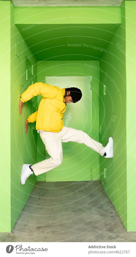 Man jumping in green corner man building passage energy activity house style active male street residential urban motion action bright colorful move outerwear