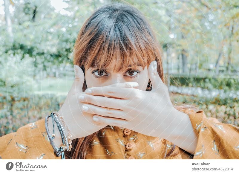 Portrait of a young red head woman covering his mouth with his hands, protest representation image freedom speech concept. Person serious young people concerned about the future