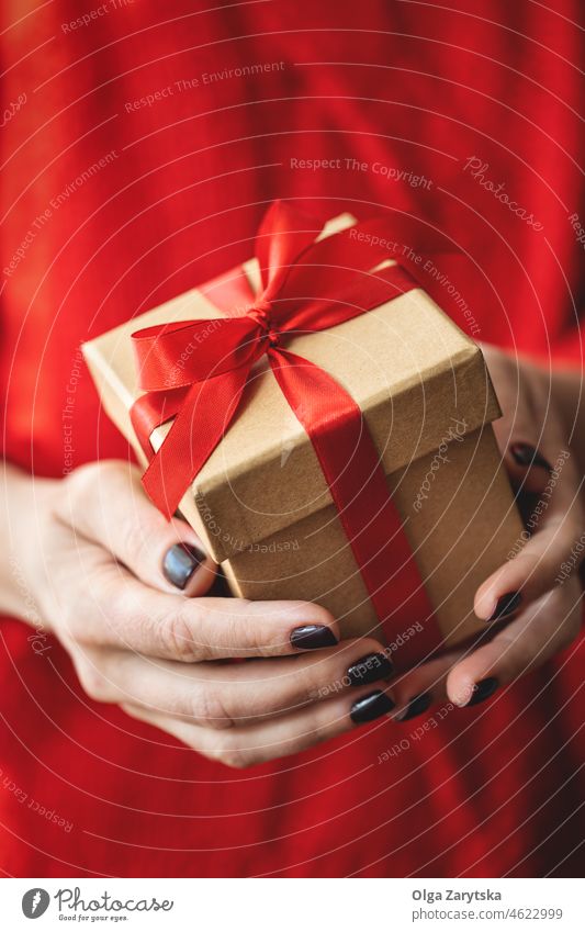 Female hands holding a gift. box red valentine christmas present day giving holiday closeup copy space giftbox birthday premium bright new year female sweater