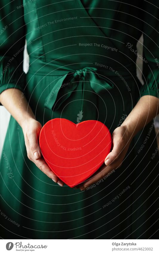 Woman's Hands holding a red heart. valentine present gift hand giving love woman green dress emerald holiday surprise charity care greeting symbol