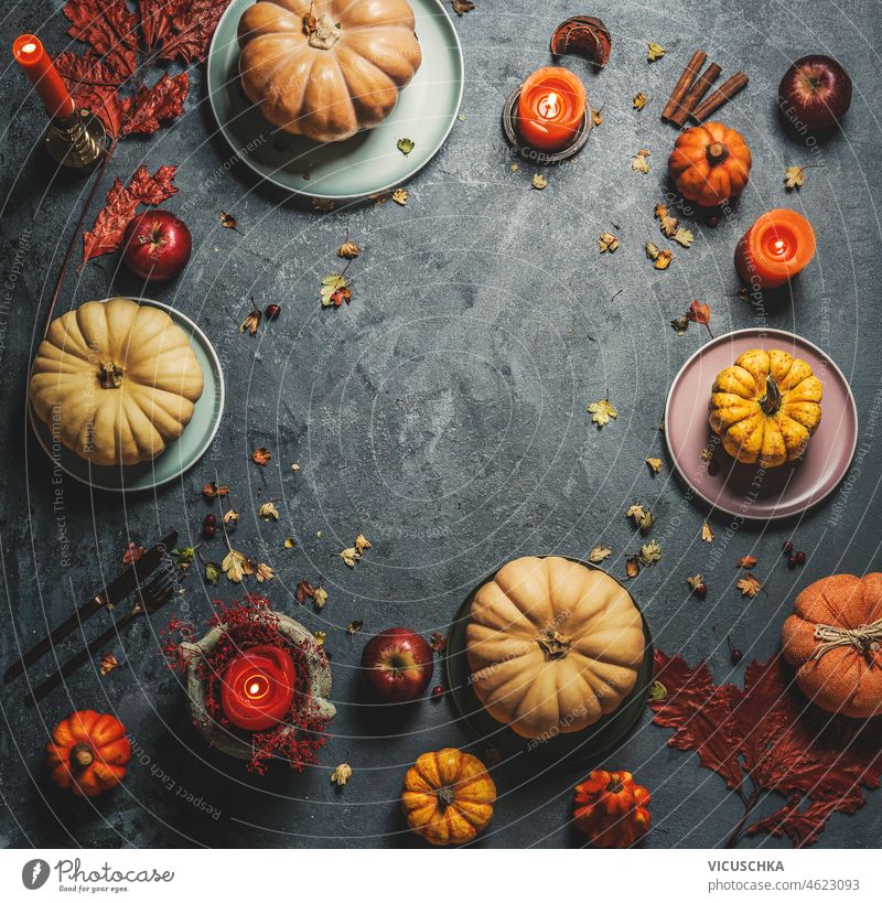 Various pumpkins on plates with orange candles, cutlery and autumn leaves on dark rustic background. Frame various top view frame orange color cinnamon