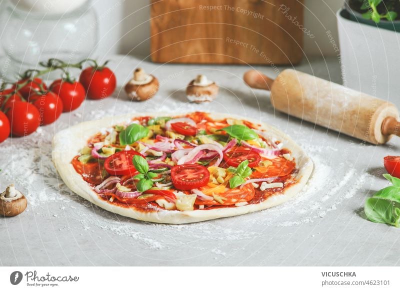 Homemade pizza preparation on light table with rolling pin and ingredients, top view homemade vegetable lunch cuisine italian food cooking delicious dough