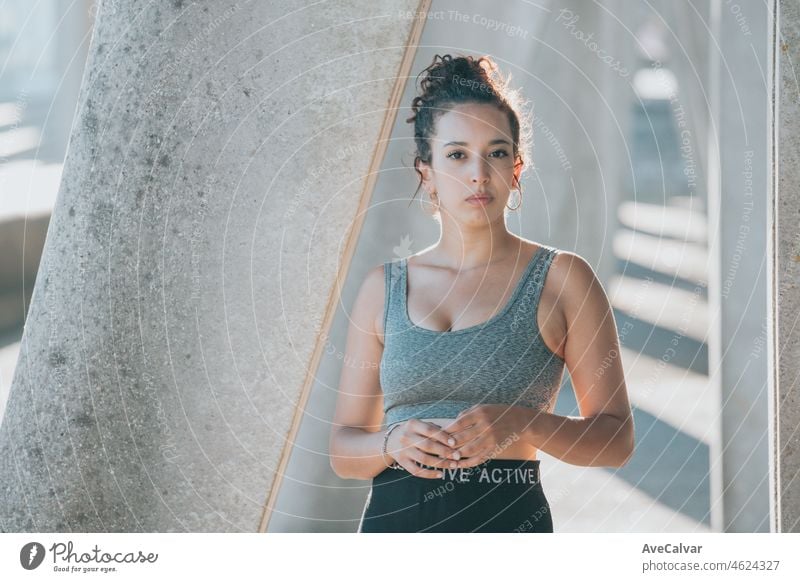Young arab african woman on training sport wear leggins portrait looking serious straight to the camera during a training session. Serious to camera, young athlete urban city background copy space