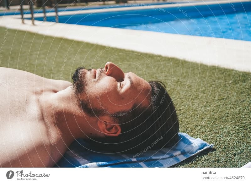 YOung man enjoying a sunbath at the swimming pool skin relax male holidays summer summertime contagious risk protection influenza green grass sunny hot warm