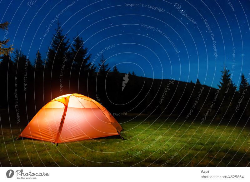 Illuminated tent in night forest mountains illuminated stars nature landscape red orange yellow outdoor light travel sky tree grass pine summer hiking camp