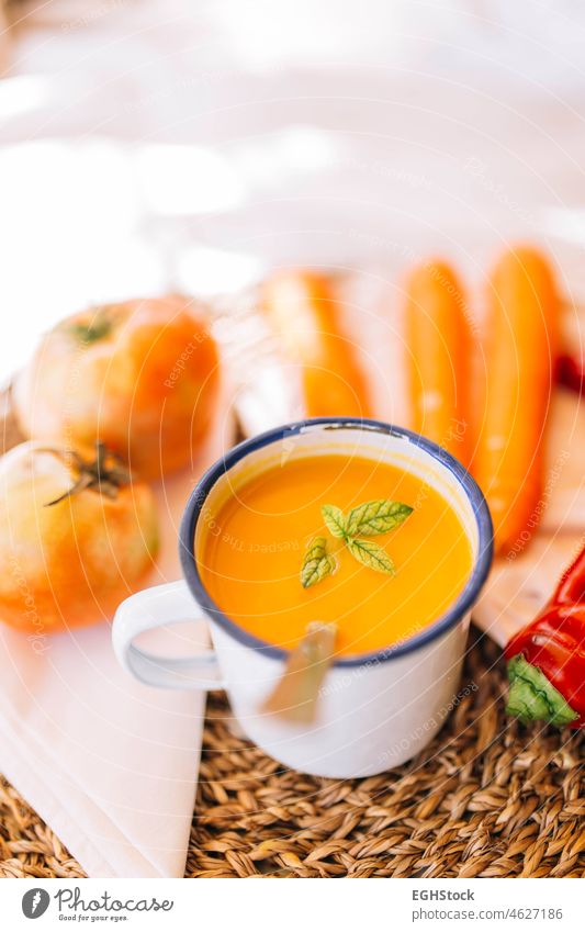 Vegan pumpkin cream in an enameled mug with vegetables, peppers leek and tomatoes soup food bowl meal autumn orange healthy squash rustic creamy nutrition