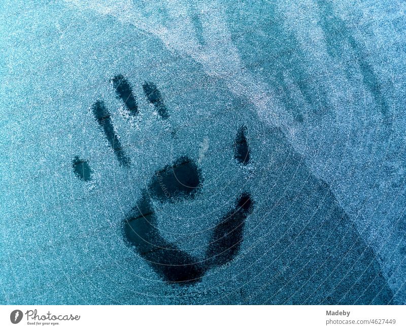 Imprint of a child's hand on the rear window of an old car iced over by hoar frost in winter in Oerlinghausen near Bielefeld on the Hermannsweg in the Teutoburg Forest in East Westphalia-Lippe