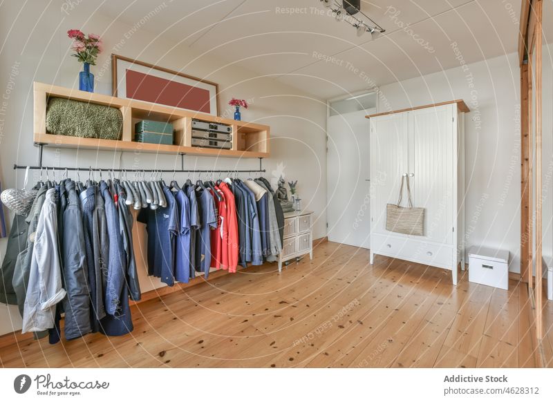 Interior of dressing room with clothes hanging on rack and wooden furniture wardrobe garment hanger closet cupboard old fashioned interior parquet style design