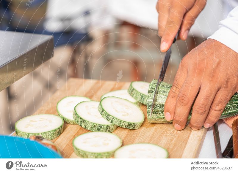 Crop man slicing ripe zucchini with knife on cutting board cook prepare kitchen food vegetable fresh chop slice culinary ingredient meal recipe nutrition