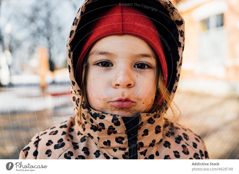 Little girl with dirty mouth on winter day kid street city childhood childish cold outerwear eat season warm clothes wintertime hat adorable leisure pastime
