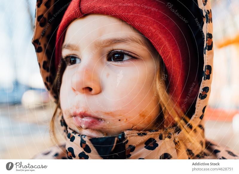 Little girl with dirty mouth on winter day kid street city childhood childish cold outerwear eat season warm clothes wintertime hat adorable leisure pastime