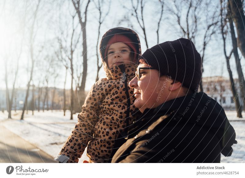 Father carrying daughter on winter day father fatherhood park kid street childhood snow pastime city cold outerwear season warm clothes wintertime hat adorable