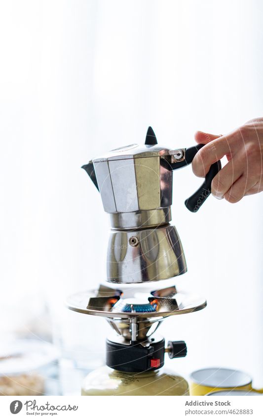 Anonymous person with moka pot in light kitchen hand coffeemaker geyser stove brew appliance modern kitchenware gas equipment stainless steel metal hot drink